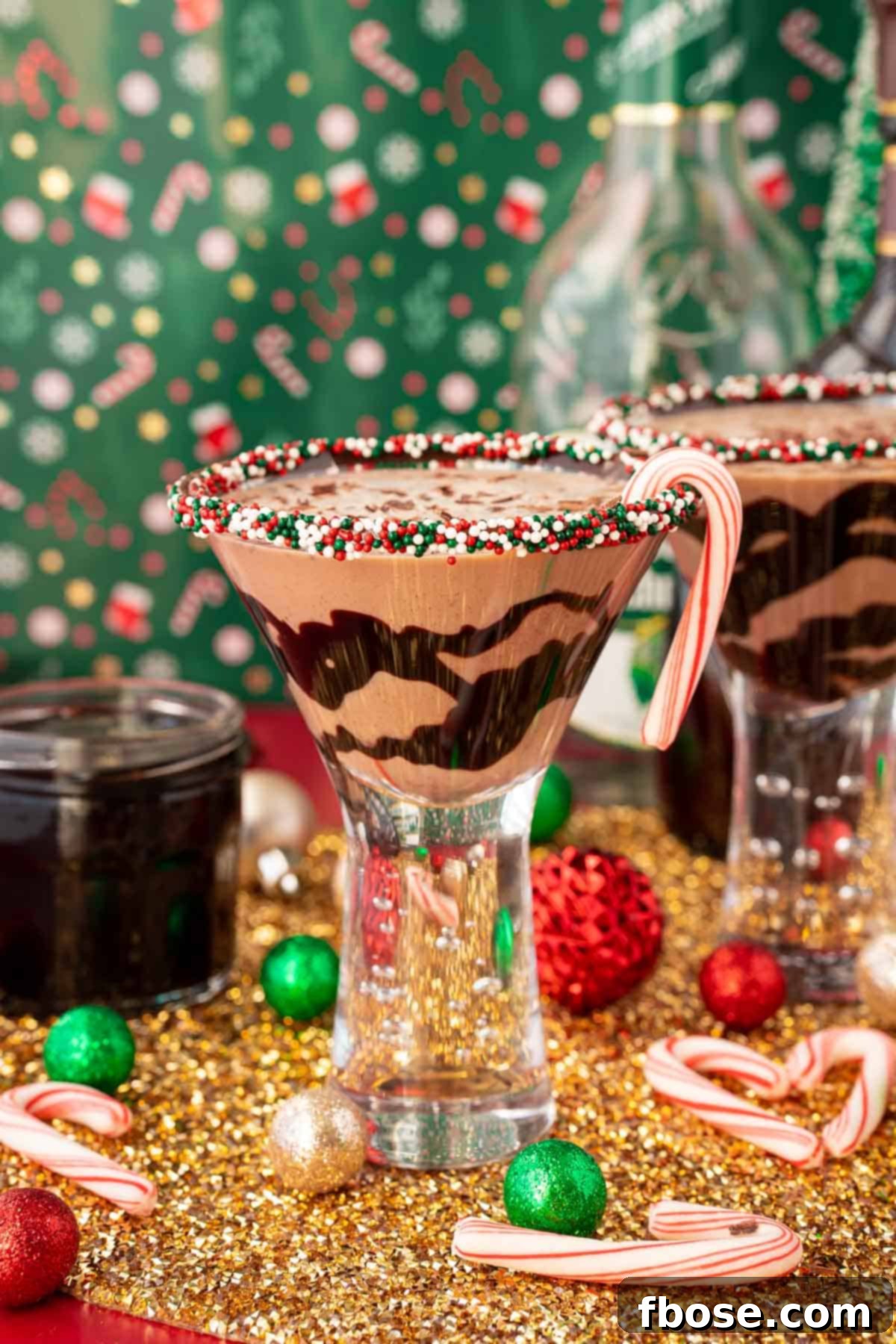 Peppermint Kiss Martini 2 A chocolate peppermint martini on a gold surface with holiday decorations scattered around it.