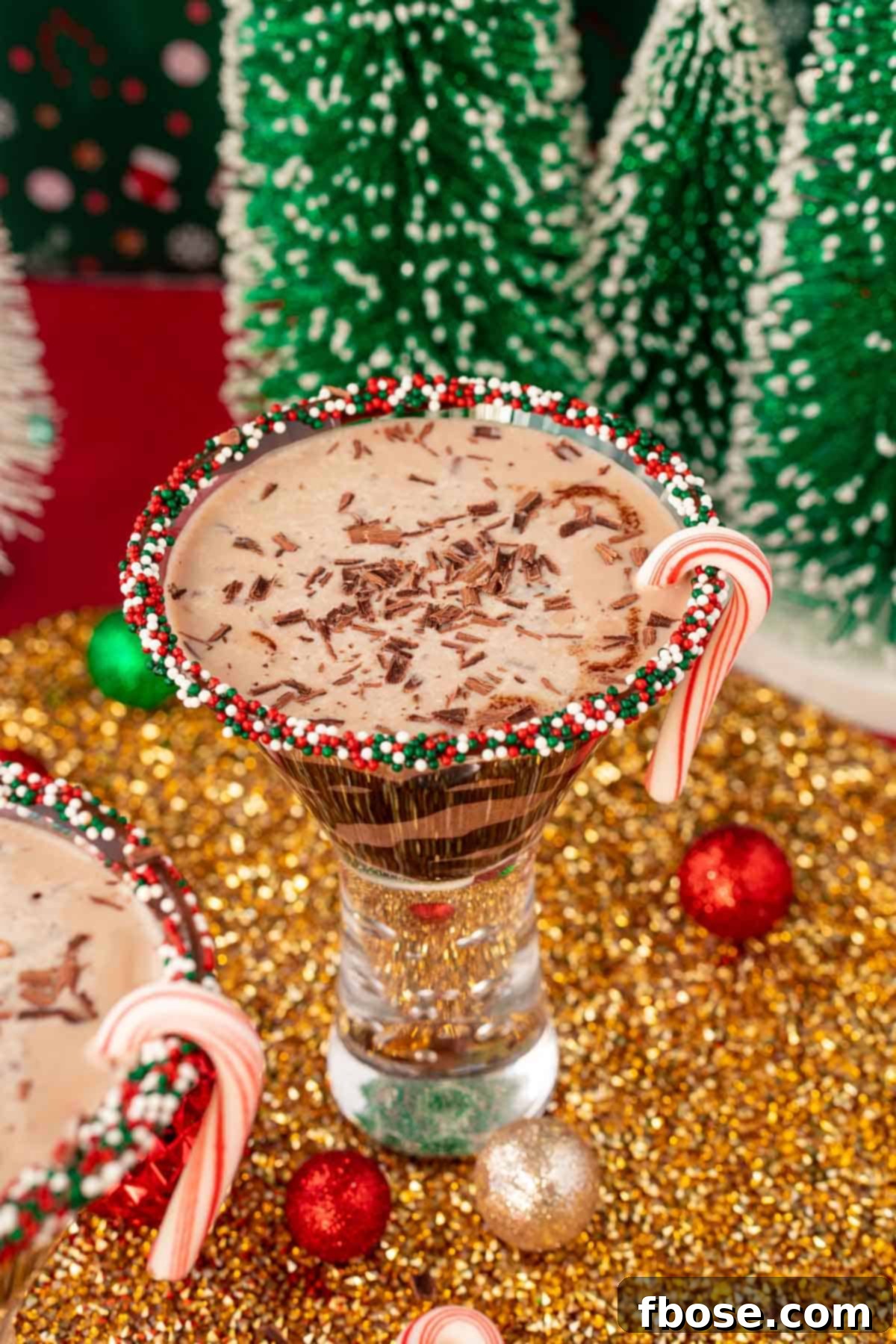 Peppermint Kiss Martini 4 Peppermint Chocolate Martini on a gold surface with holiday decorations around it.