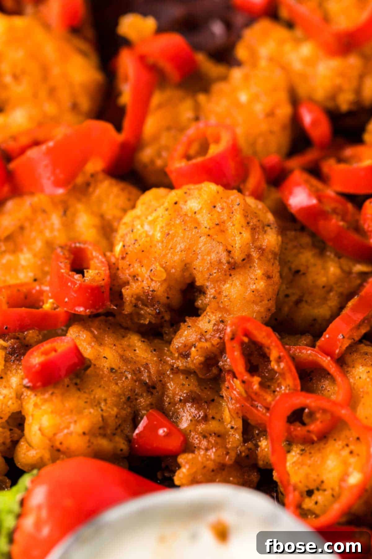 Longhorn copycat wild west shrimp on a plate with red chili peppers and dipping sauce, ready to serve.