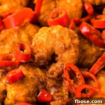 Longhorn copycat wild west shrimp on a plate with red chili peppers and dipping sauce.