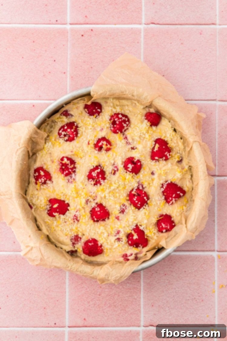 The lemon raspberry cake batter, topped with lemon-infused sparkling sugar, sits in its baking pan, ready to be placed in the oven.