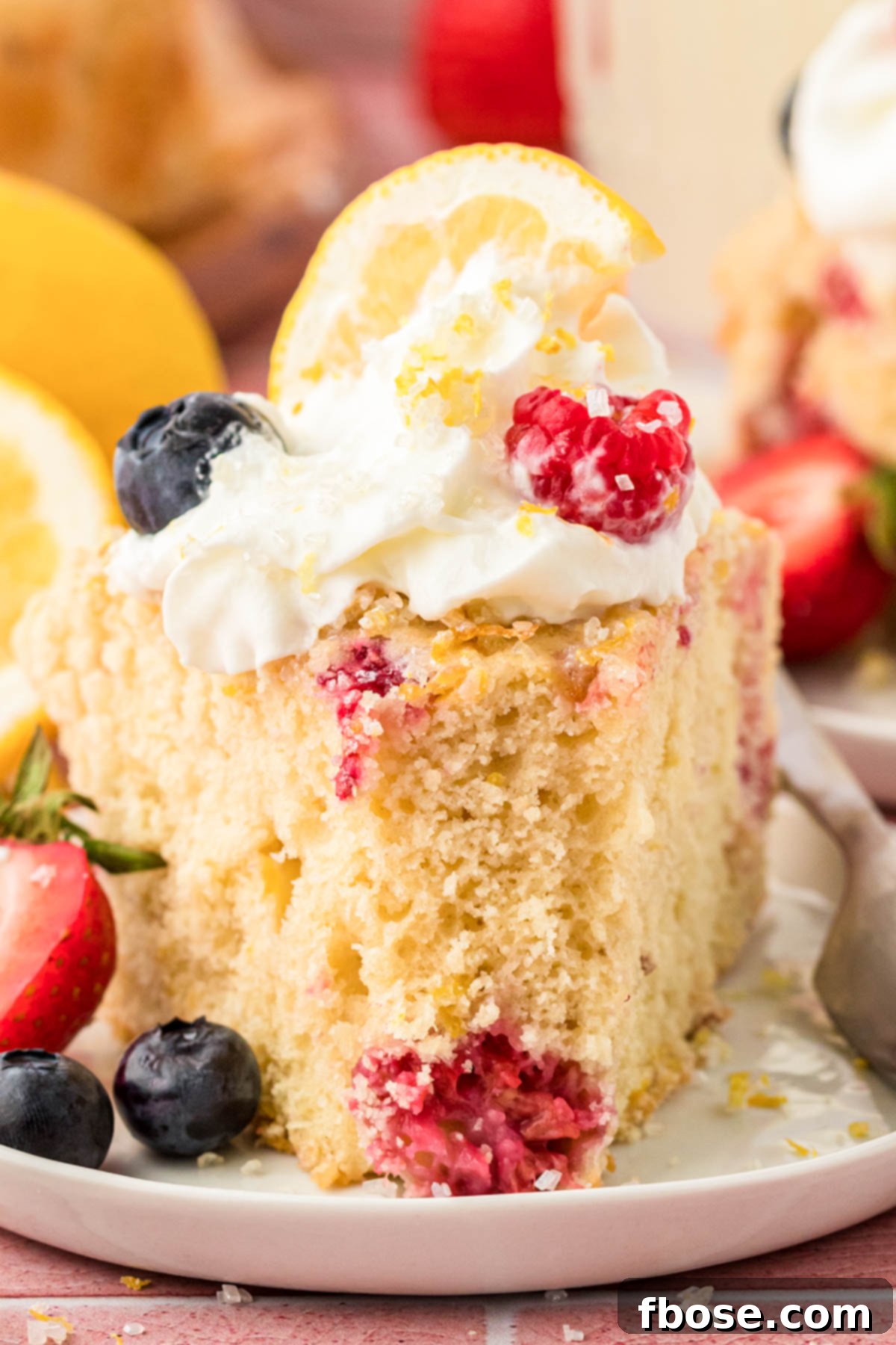 A perfectly portioned slice of Lemon Raspberry Cake artfully arranged on a small white plate, ready to be enjoyed.