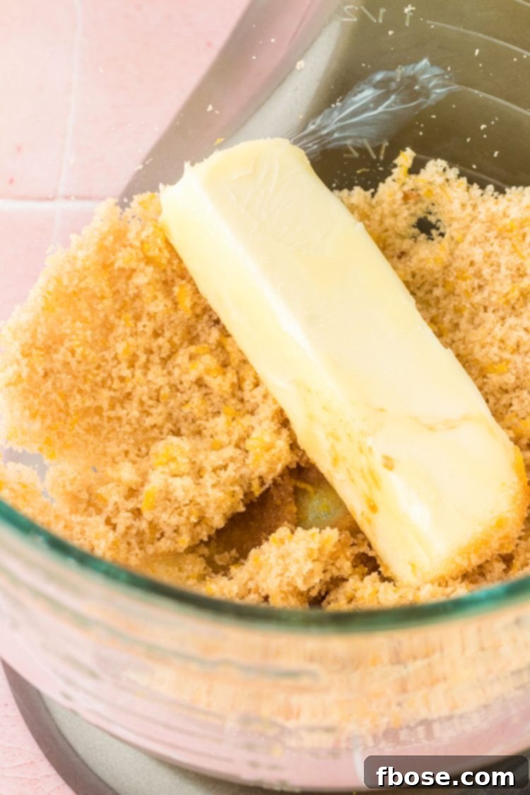 Softened butter being added to the sugar and lemon zest mixture in a stand mixer bowl, beginning the creaming process.