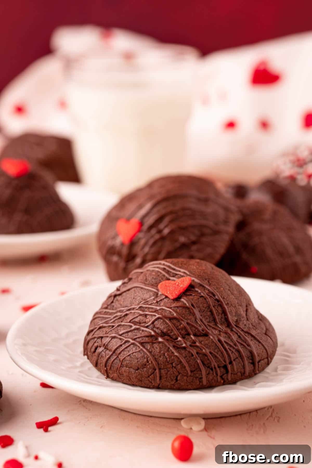 Chocolate cookies on a white plate with more cookies behind it.