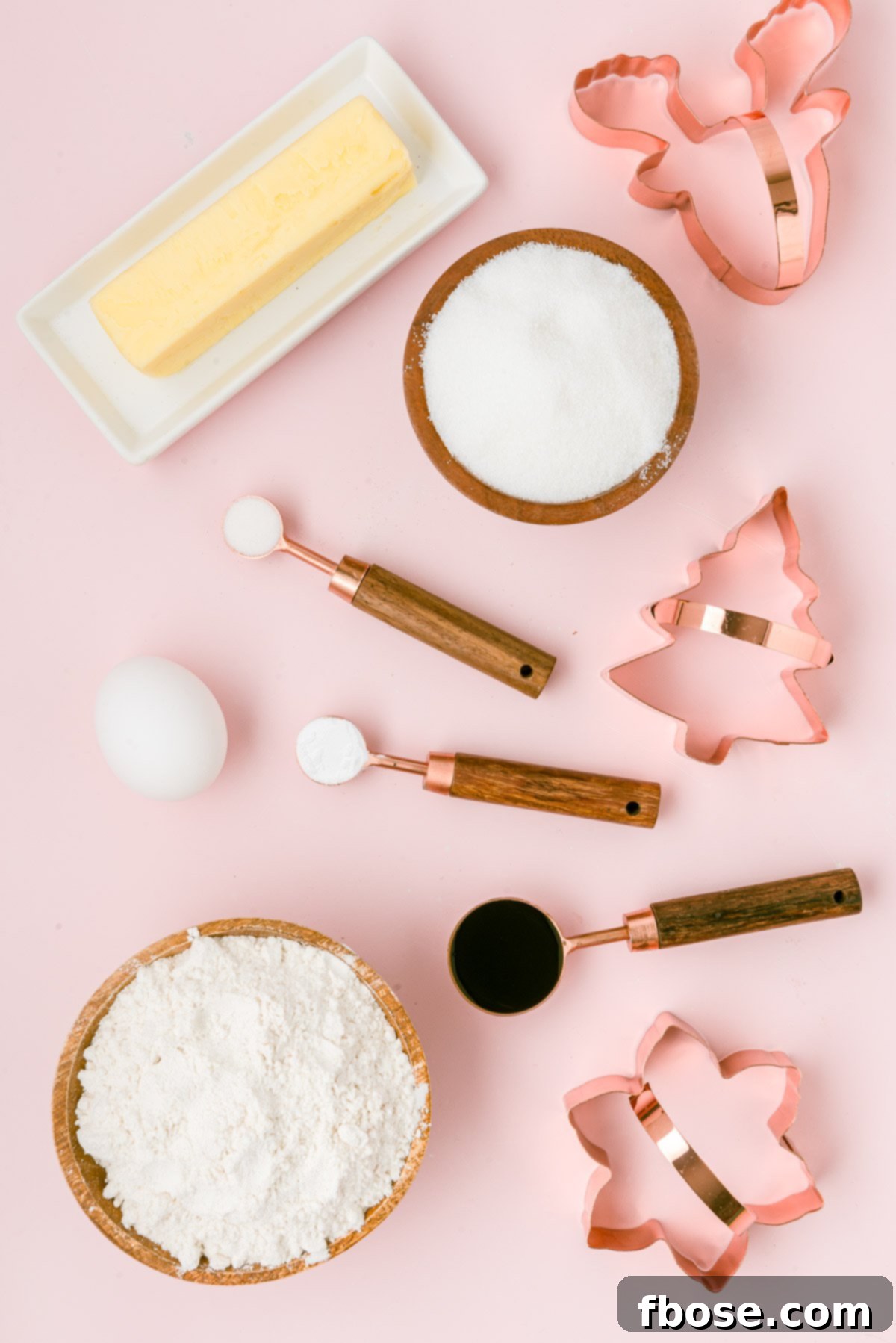 Ingredients to make cutout sugar cookies on a pink table.