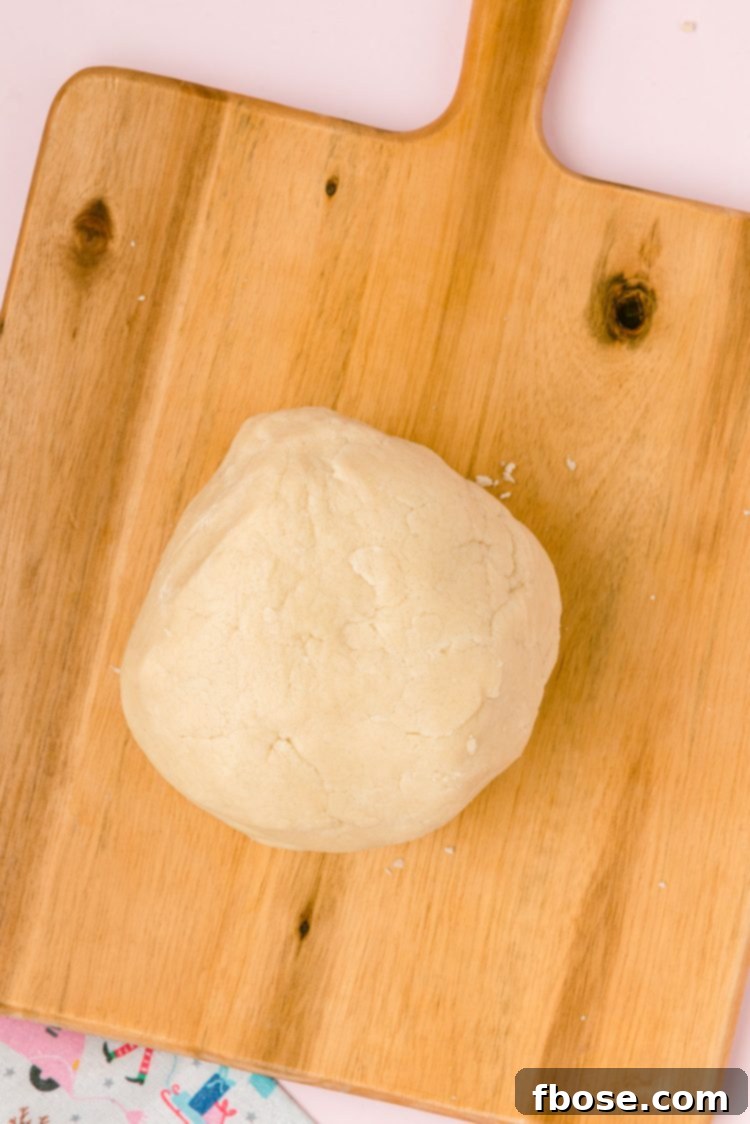 A ball of sugar cookie dough on a wooden board.