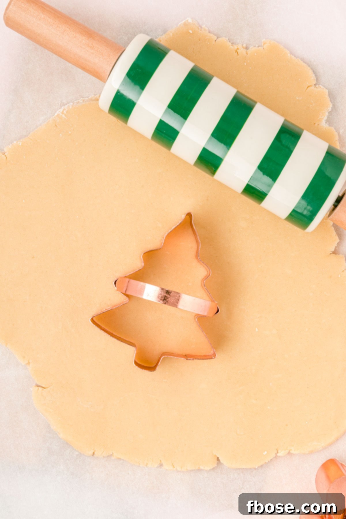 A tree cookie cutter on sugar cookie dough.