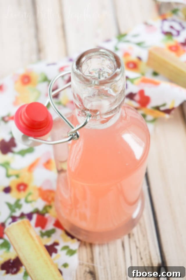 Homemade Rhubarb Simple Syrup, a vibrant pink liquid, poured over dessert or ready for drinks.