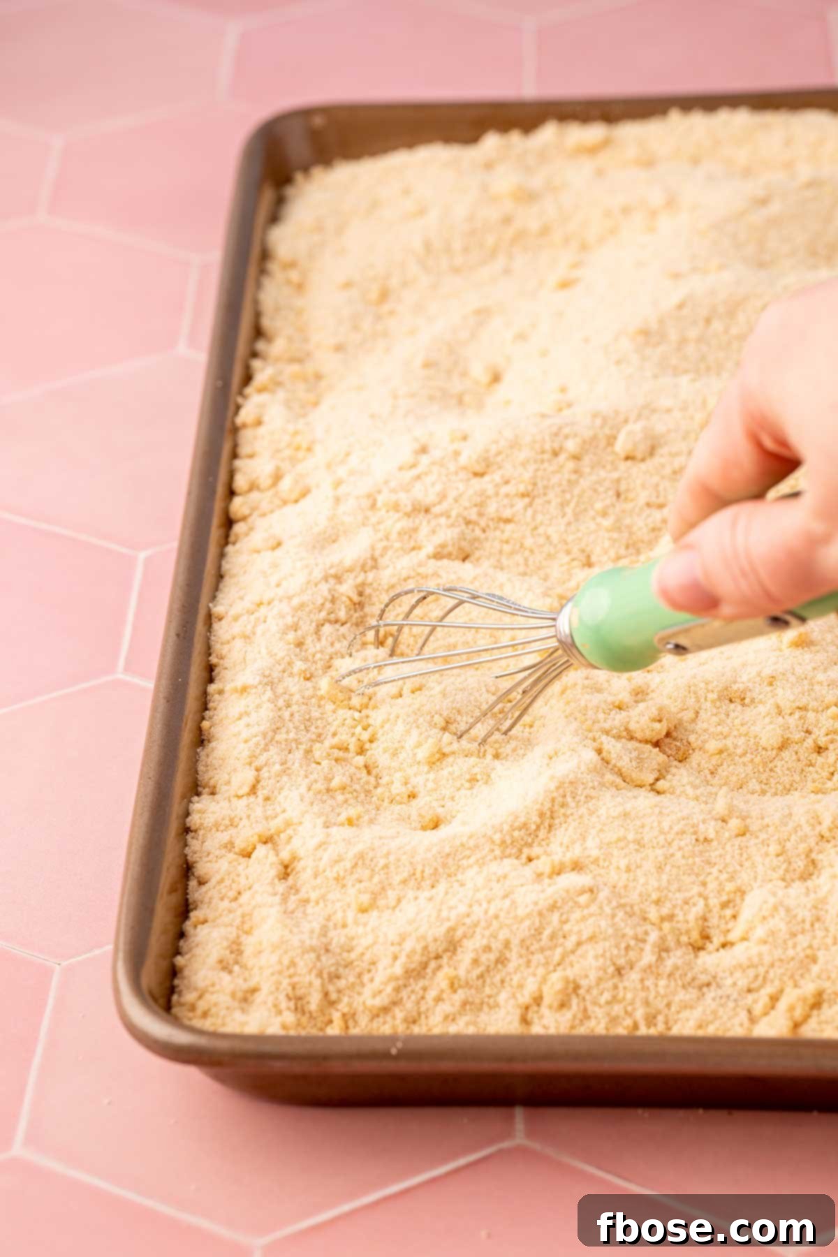 The Secret to Toasted Sugar 5 Toasted sugar being whisked on a large rimmed baking sheet to release steam and prevent clumping during cooling.