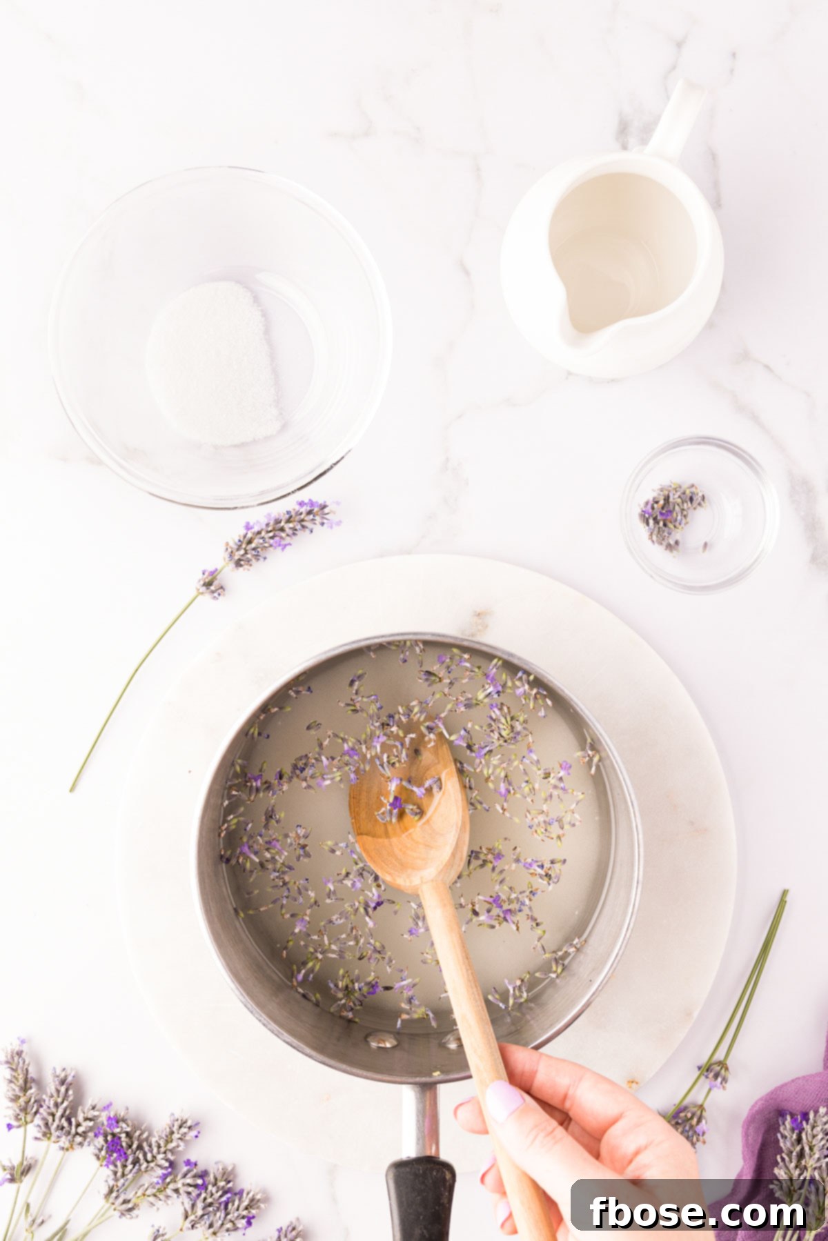 Dried lavender buds being stirred in a saucepan with water and sugar to make lavender simple syrup.