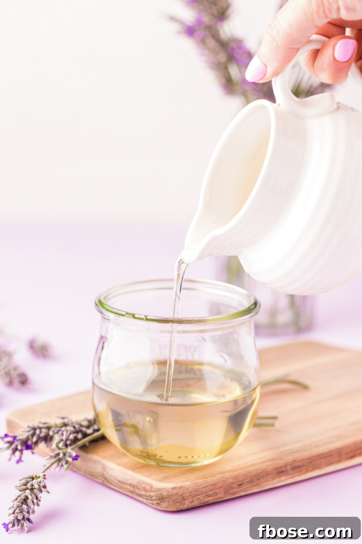 Homemade lavender simple syrup being carefully poured into a decorative glass jar.