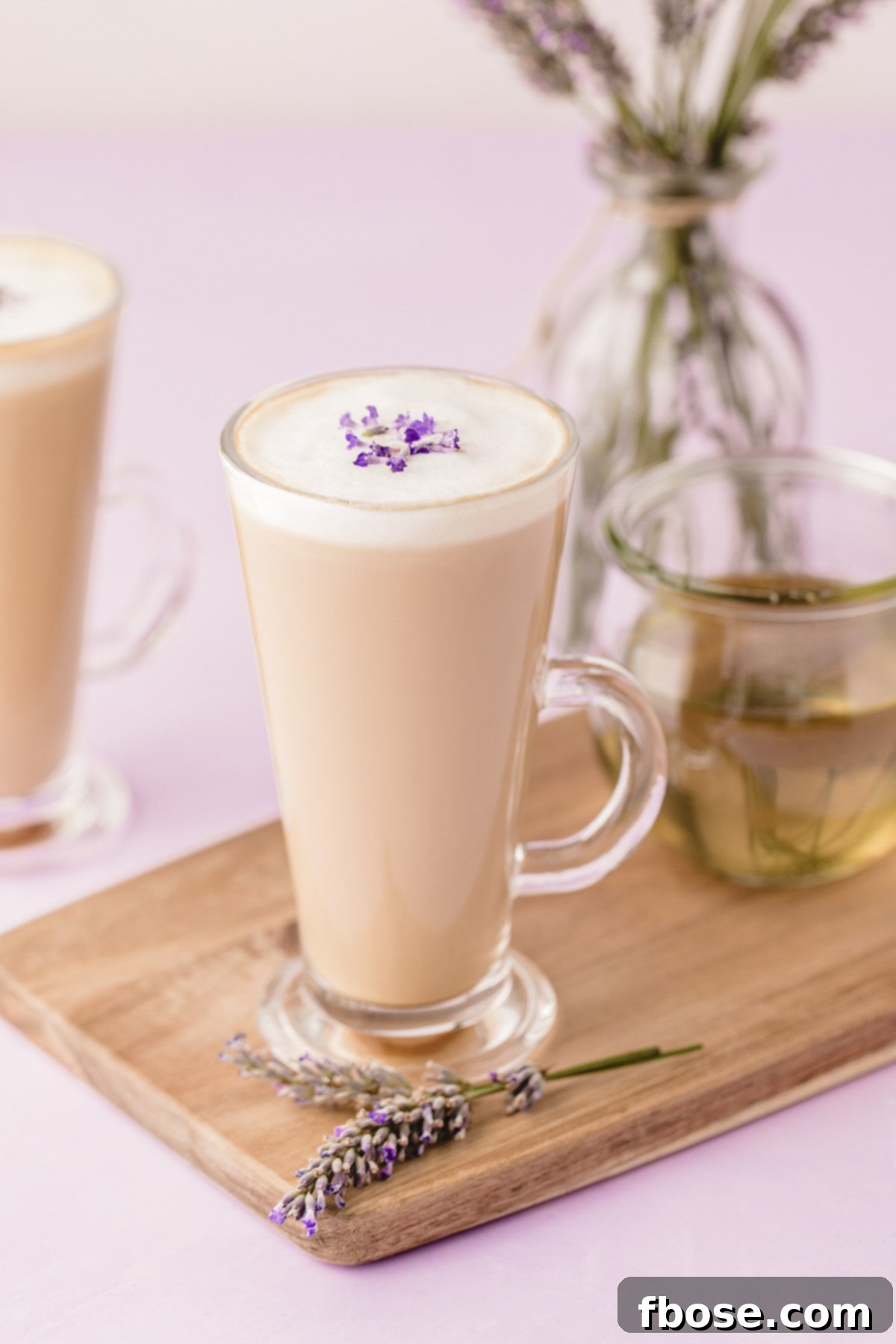 Two beautiful mugs of lavender lattes elegantly arranged on a rustic wooden serving board, resting on a soft purple surface, creating a serene and inviting scene.