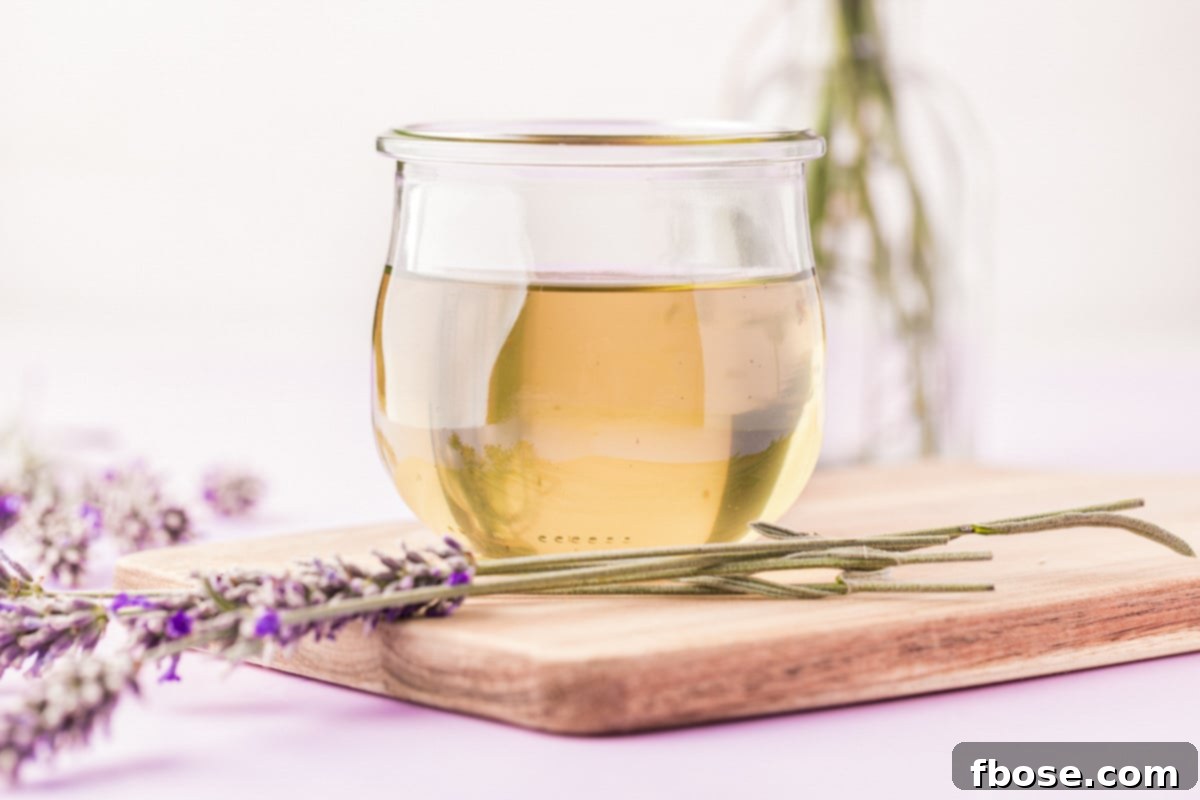 A small, elegant glass jar filled with homemade lavender simple syrup, artfully placed on a weathered wooden board, surrounded by fresh lavender sprigs.