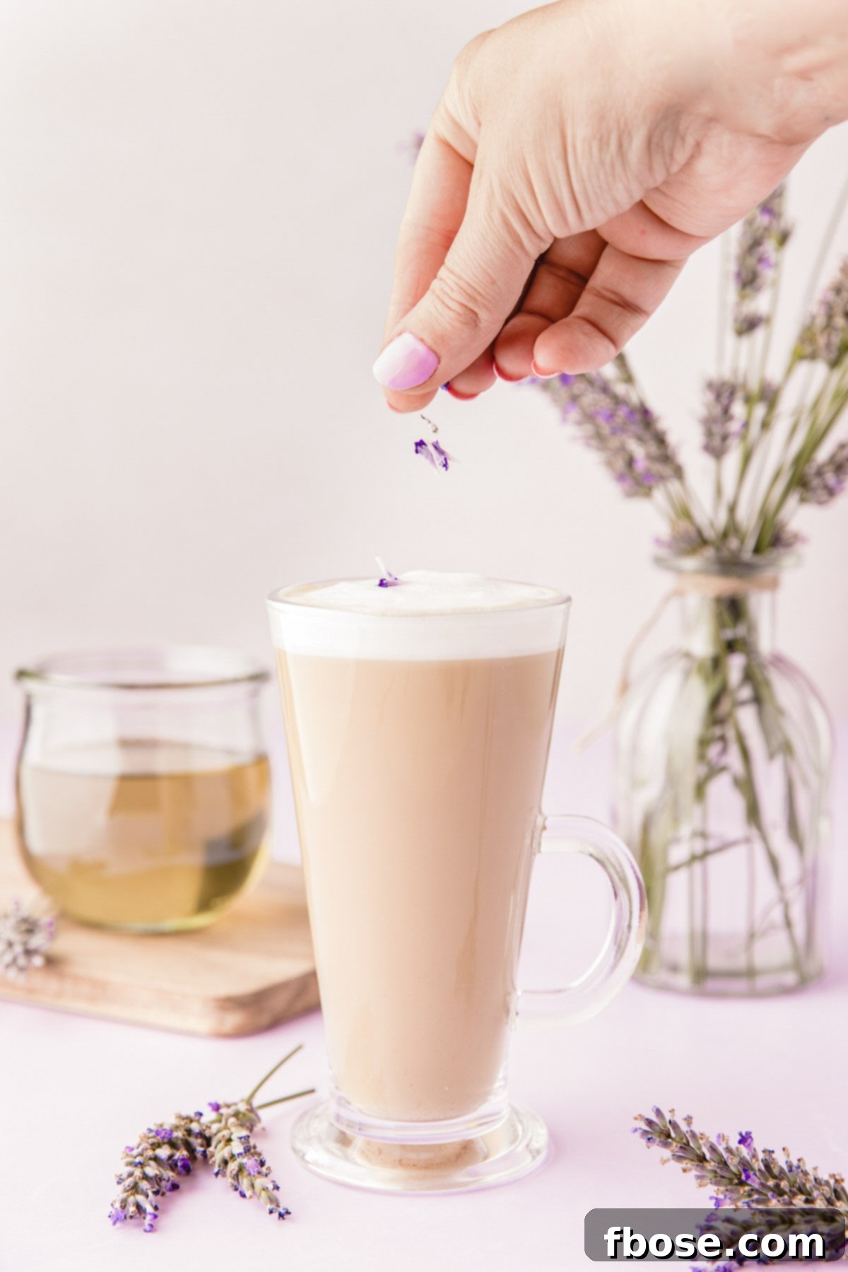 A delicate sprinkling of vibrant lavender buds falling onto the pristine white foam of a freshly prepared lavender latte, adding a beautiful aromatic garnish.