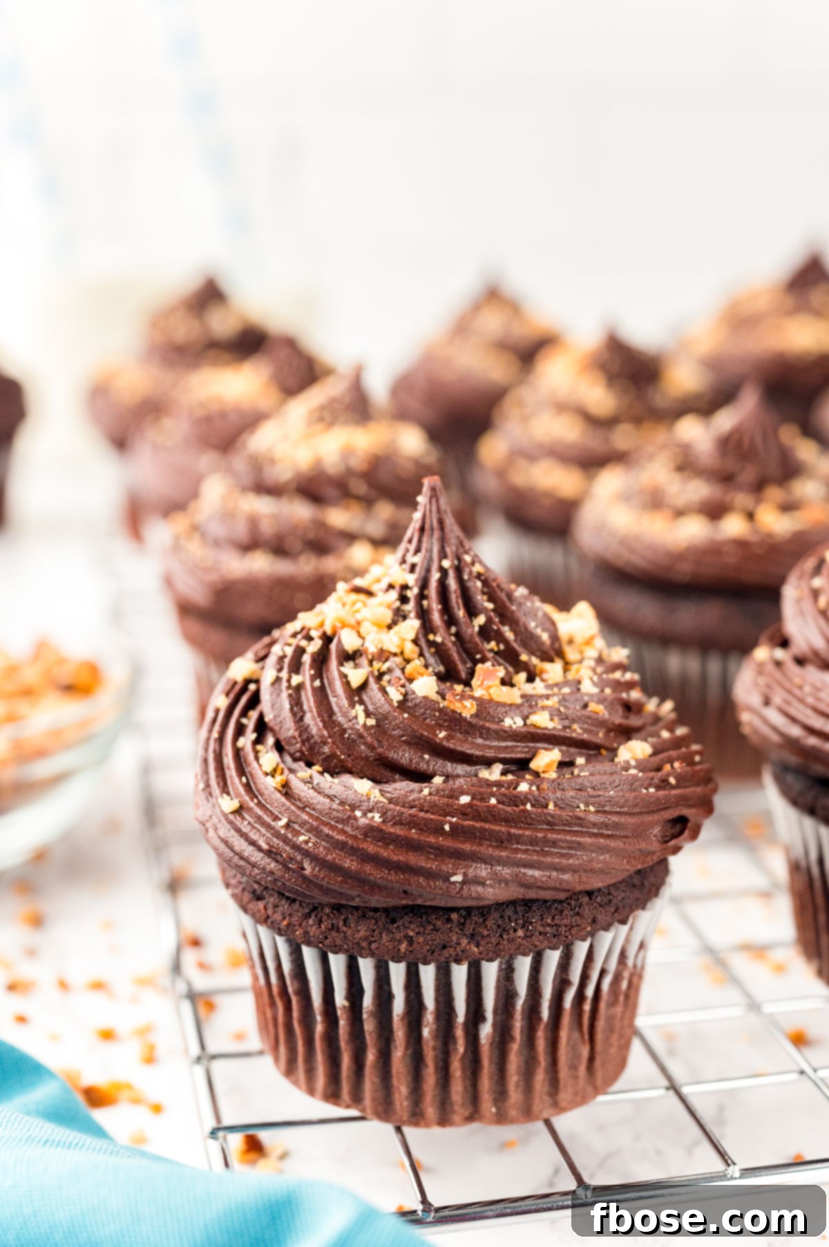 Decadent Nutella Cupcakes 10 Close up of chocolate hazelnut nutella cupcakes neatly arranged on a wire rack, highlighting their perfect frosting and chopped hazelnut topping.