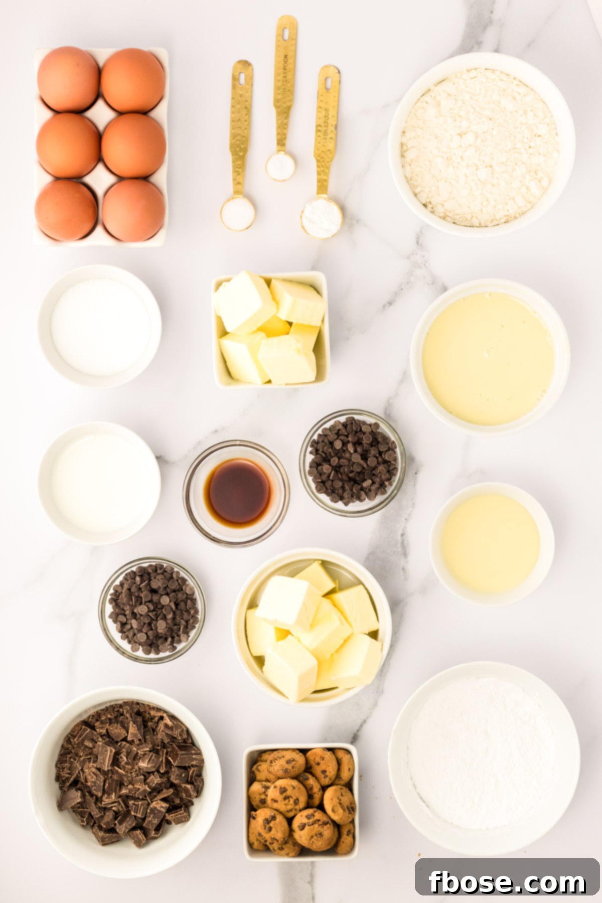 Ingredients to make milk and cookies cupcakes prepped on a marble counter.