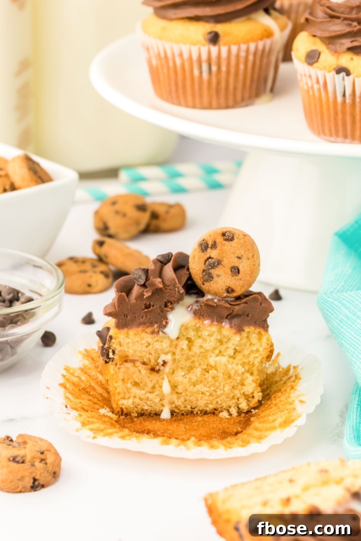 Milk and cookies cupcakes on a white table. One has been sliced in half.