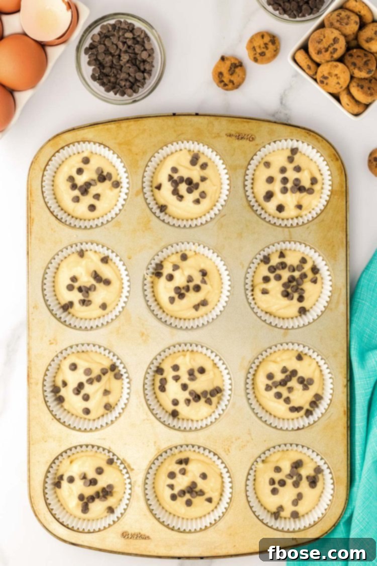 A cupcake pan filled with batter to make chocolate chip cupcakes.
