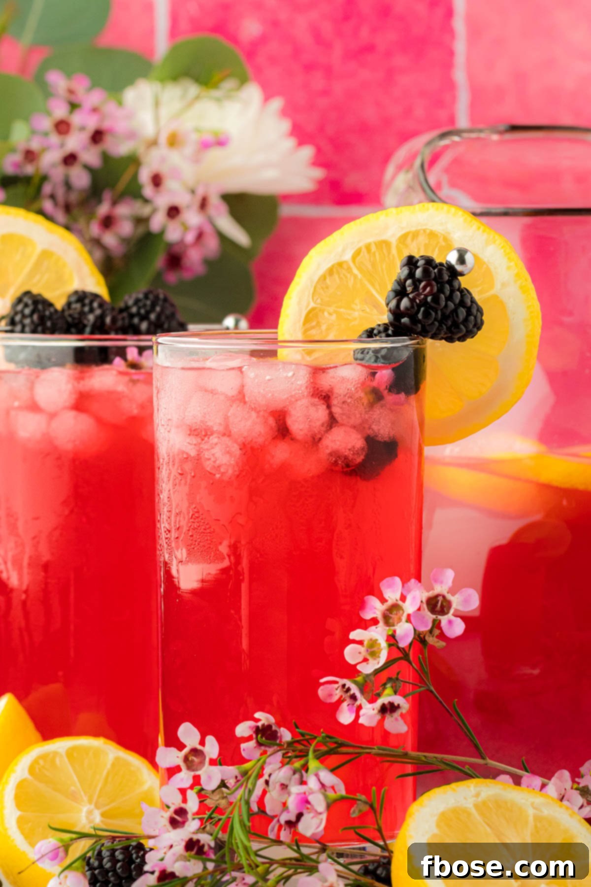Delicious Homemade Blackberry Lemonade 11 Glasses of blackberry lemonade arranged beautifully on a table, ready for serving, showcasing the drink's appealing color and garnishes.
