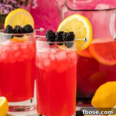 Two glasses of blackberry lemonade on a counter.