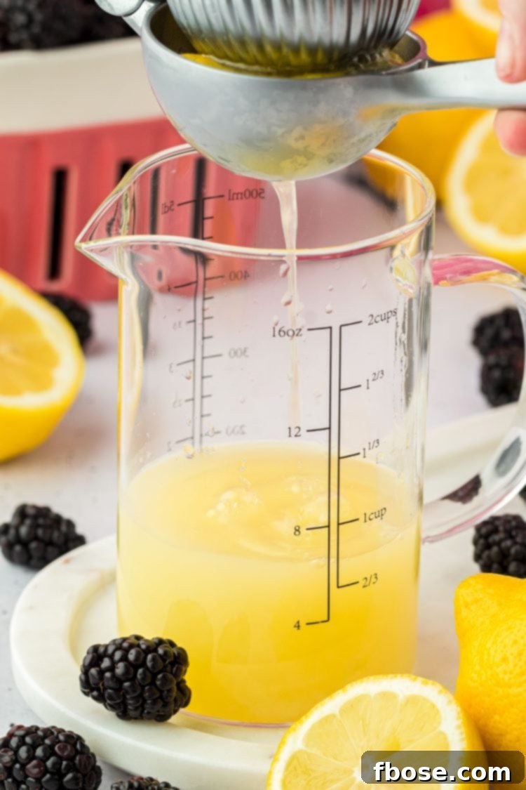Delicious Homemade Blackberry Lemonade 6 Juicy roasted lemons being squeezed with a citrus press, with the fresh lemon juice collecting in a clear measuring cup below.