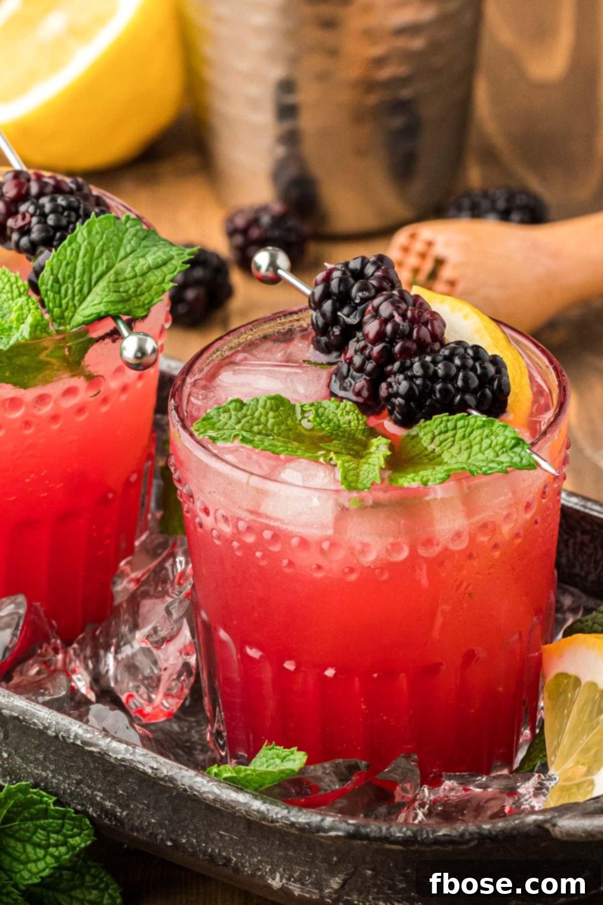 Blackberry Bourbon Smash in a black cocktail tray, garnished with fresh blackberries and mint.