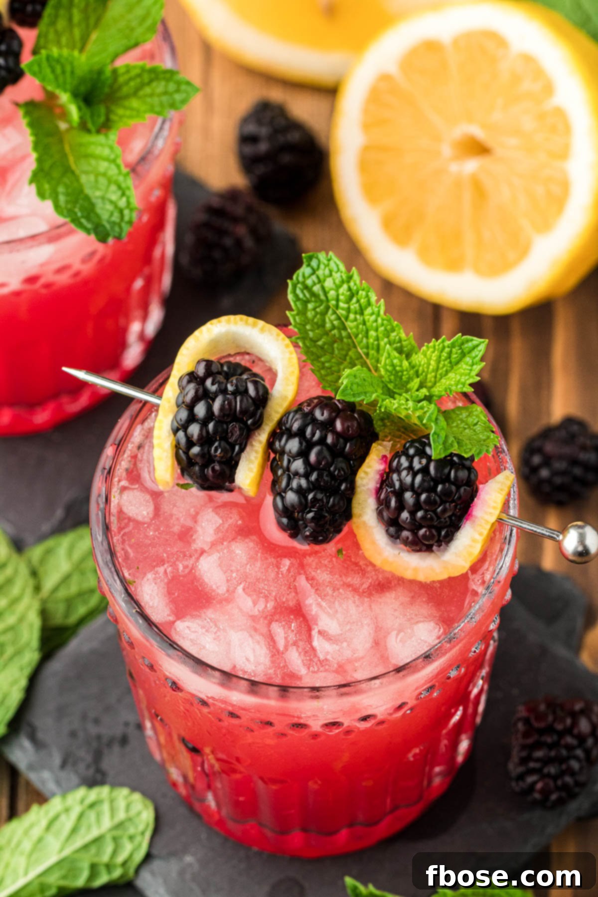 Blackberry Bourbon Smash on a slate coaster, garnished with fresh mint and berries.