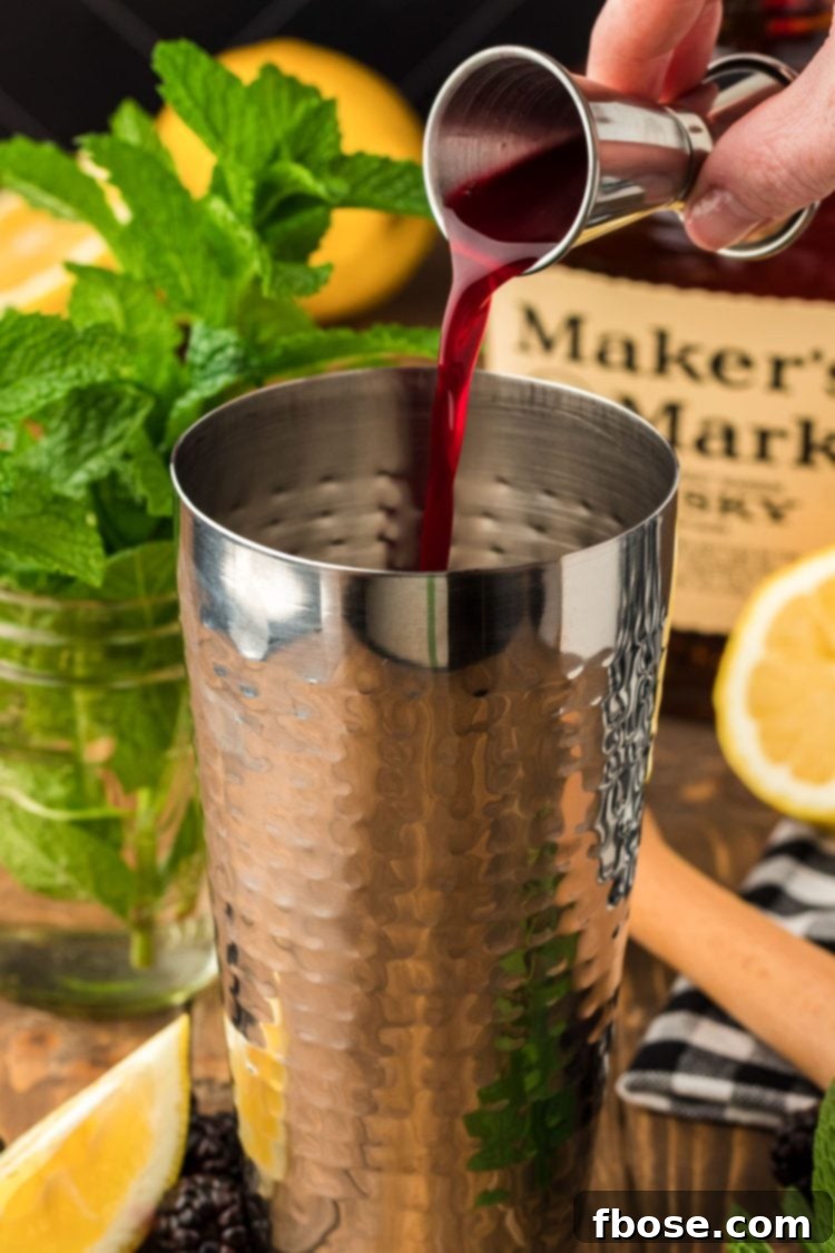 Blackberry simple syrup being poured into a silver cocktail shaker.