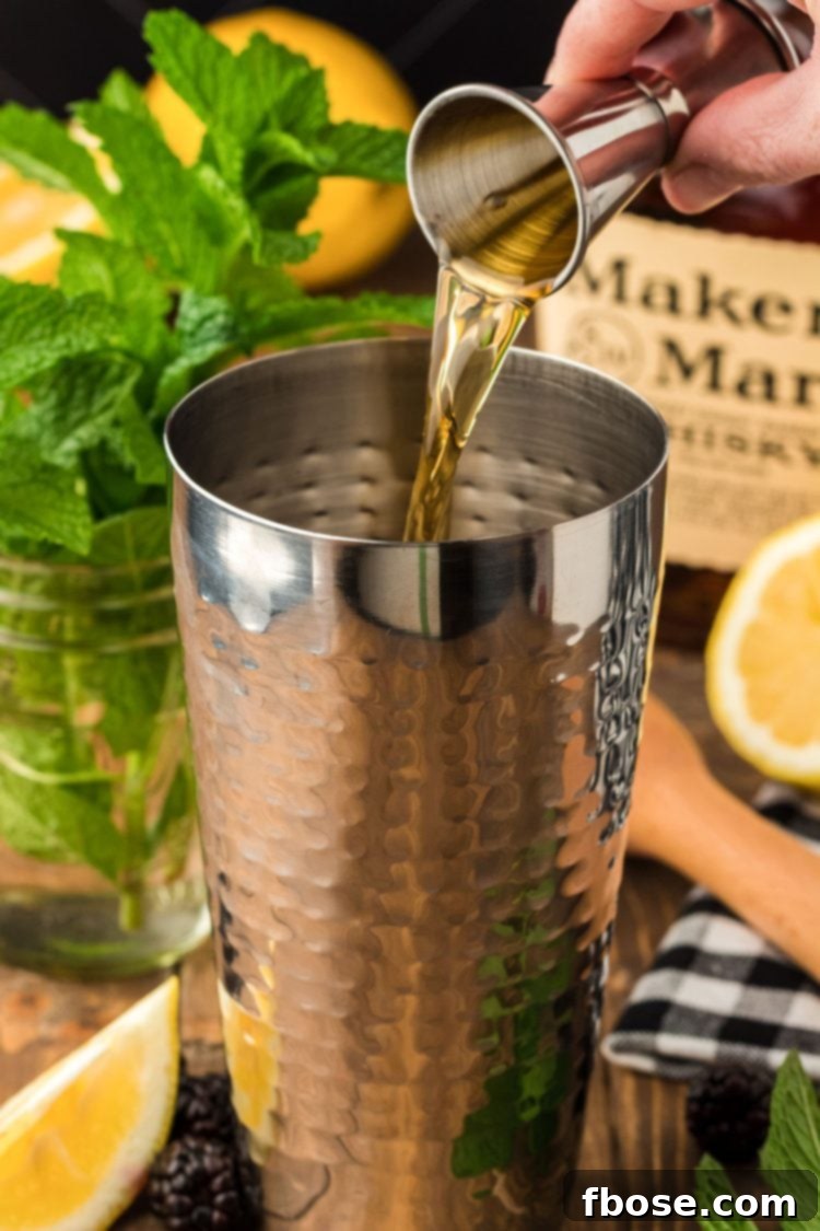 Bourbon whiskey being poured into a cocktail shaker with other ingredients.