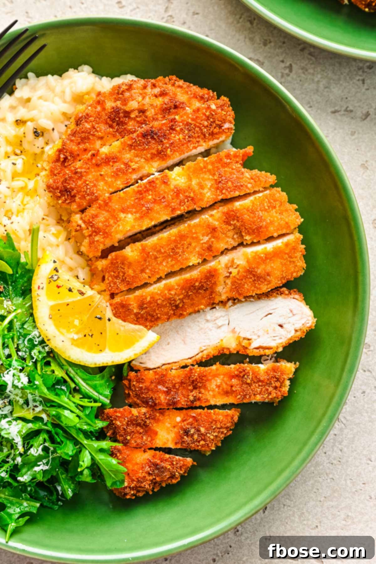 Overhead photo of golden-brown panko chicken in a green bowl, served with fluffy white rice and fresh green salad.