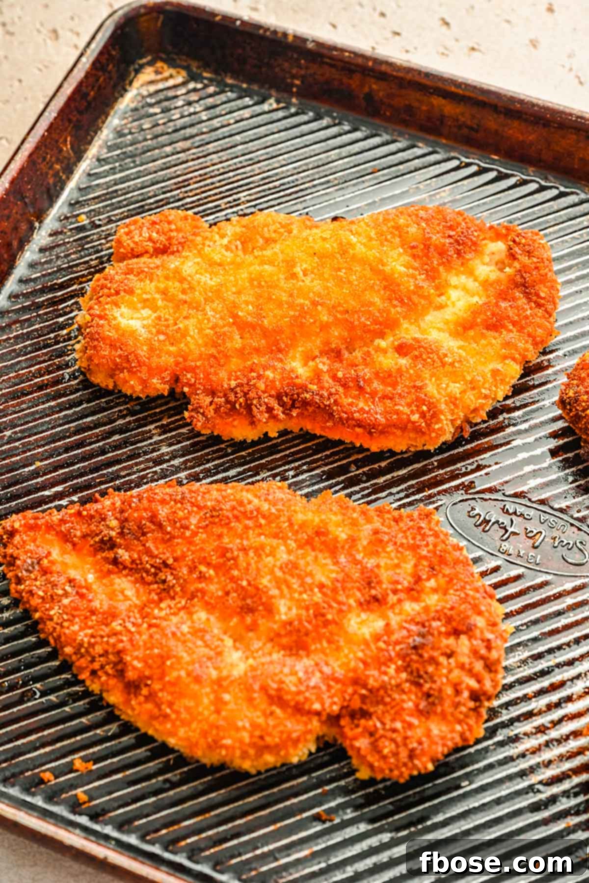Crispy panko breaded chicken pieces arranged neatly on a parchment-lined baking sheet after baking.