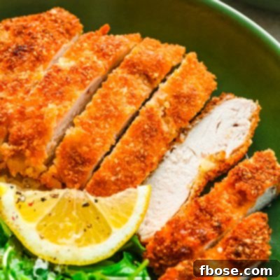 Overhead photo of panko chicken in a green bowl with rice and greens.