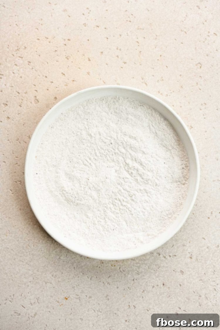 A white bowl containing a finely mixed blend of flour and various spices.