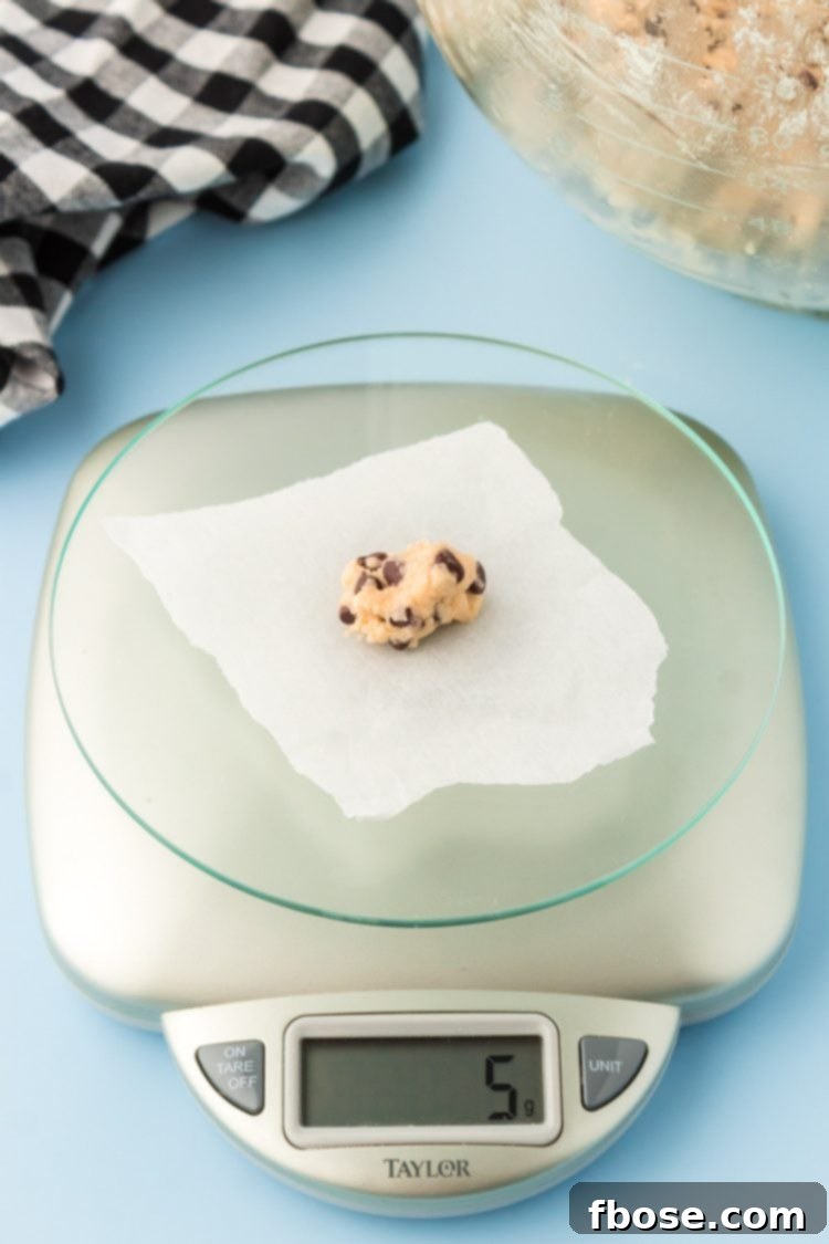 Cookie dough being portioned out of a kitchen scale to make itty bitty chocolate chip cookies.