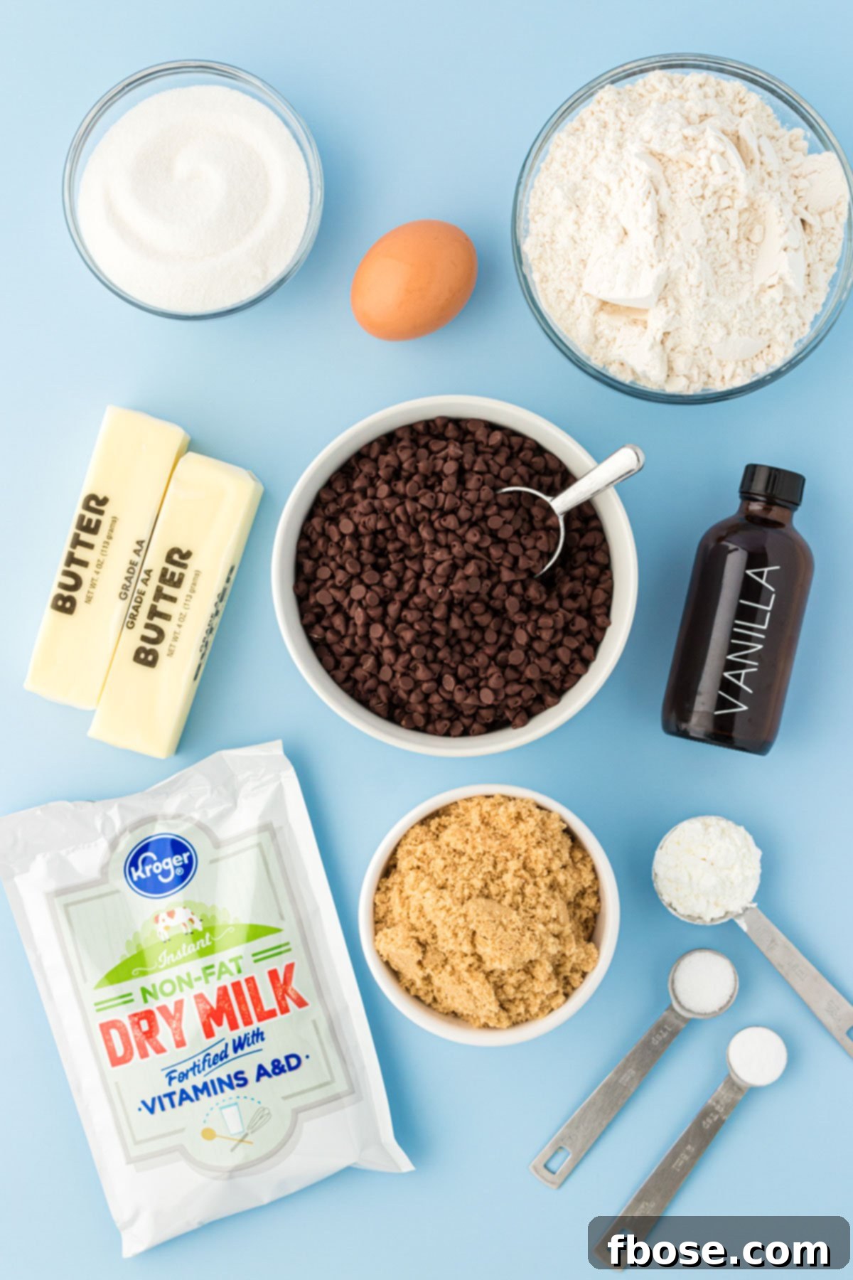 Overhead photo of ingredients to make mini chocolate chip cookies on a blue surface.