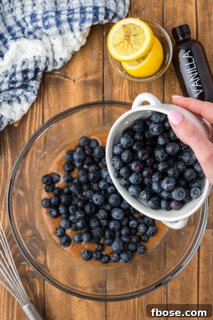 Blueberries being added to a bowl with butter, cinnamon, sugar, and more.