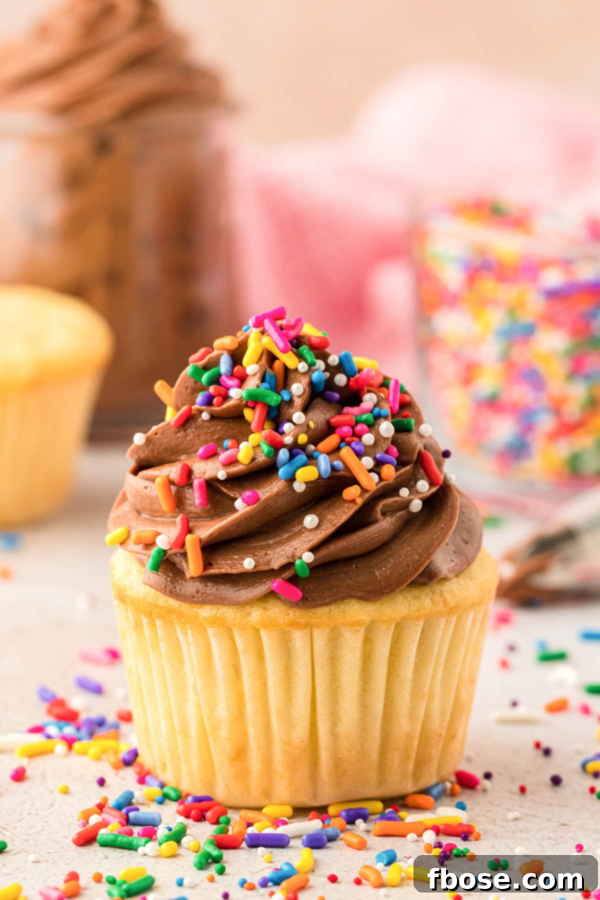 Yellow cupcakes with chocolate frosting and rainbow sprinkles, ready to be enjoyed.