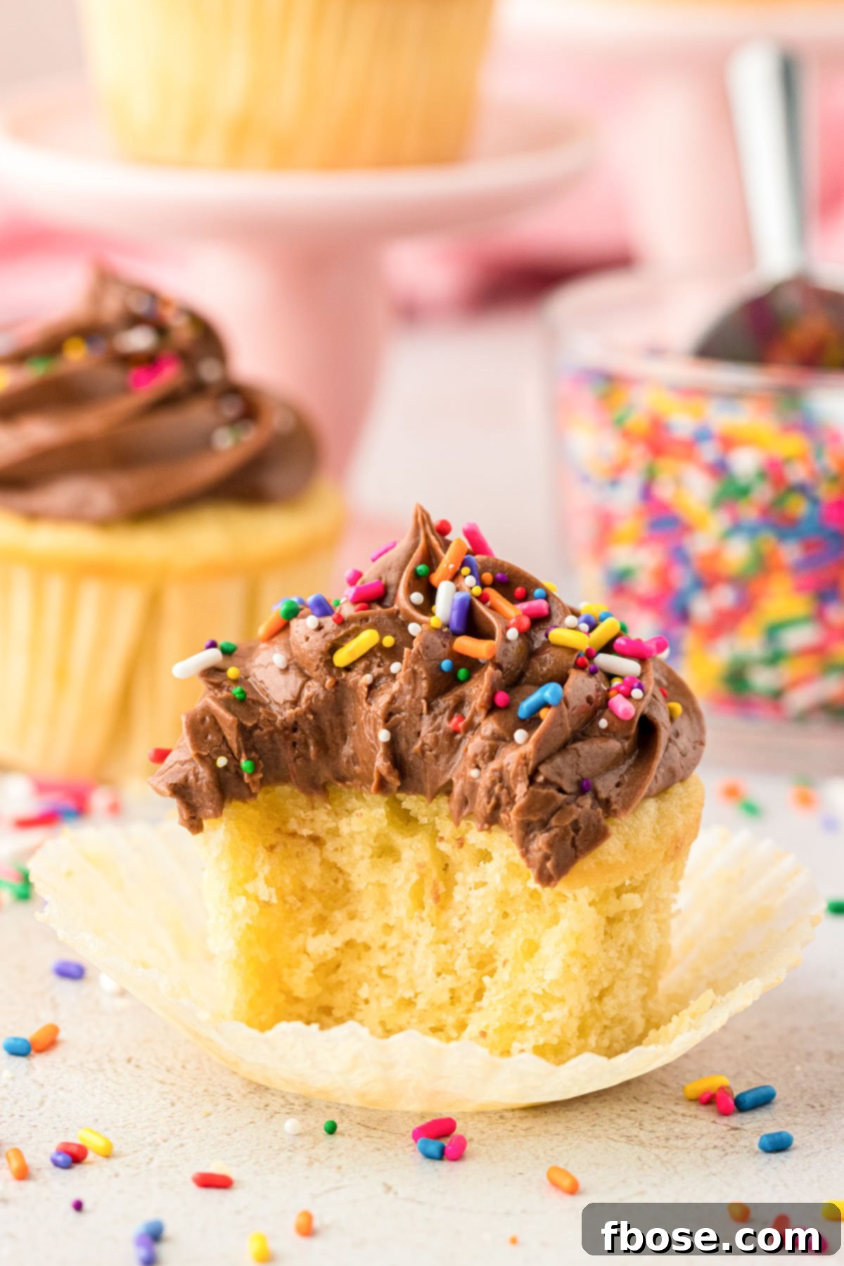 A delightful yellow cupcake with chocolate frosting, taking a bite out of it, revealing its tender interior.