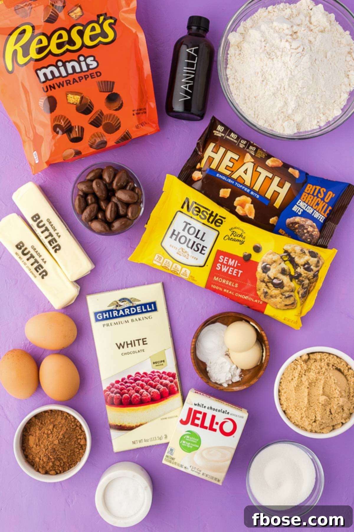 An overhead shot of various Kitchen Sink Cookie ingredients neatly arranged on a vibrant purple surface, ready for baking.