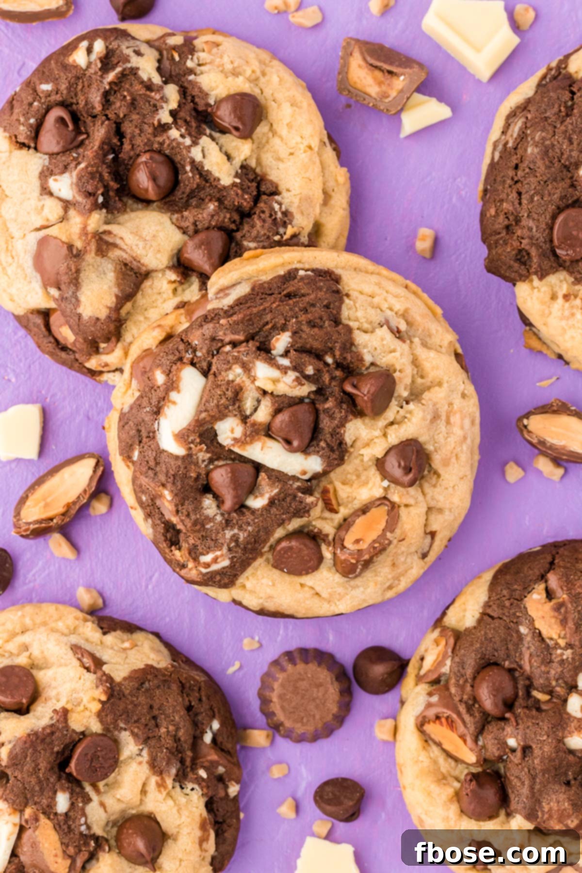 An overhead view of multiple Kitchen Sink Cookies on a purple surface, highlighting their irregular shapes and generous mix-ins.