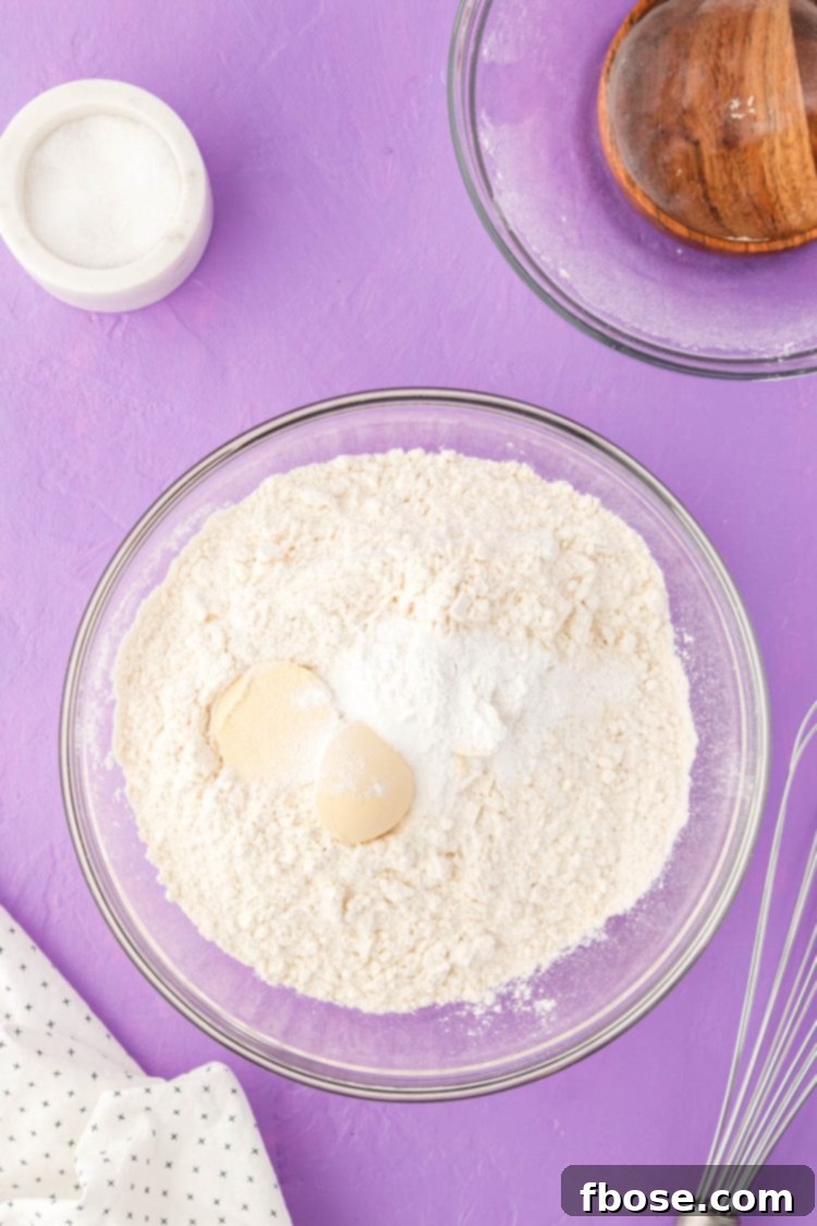 A selection of dry ingredients for cookies, including flour and leavening agents, perfectly mixed in a separate glass bowl.