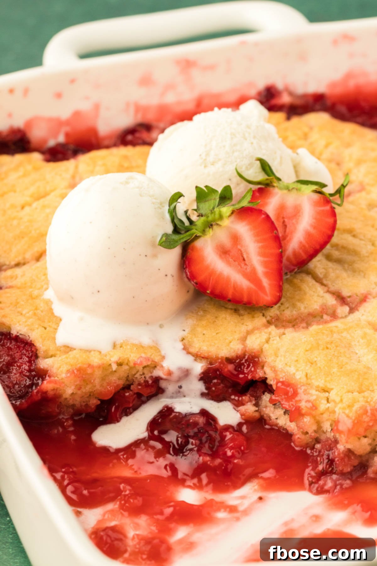 Classic Strawberry Cobbler 2 Two scoops of vanilla ice cream on a pan of strawberry cobbler, ready to be served.