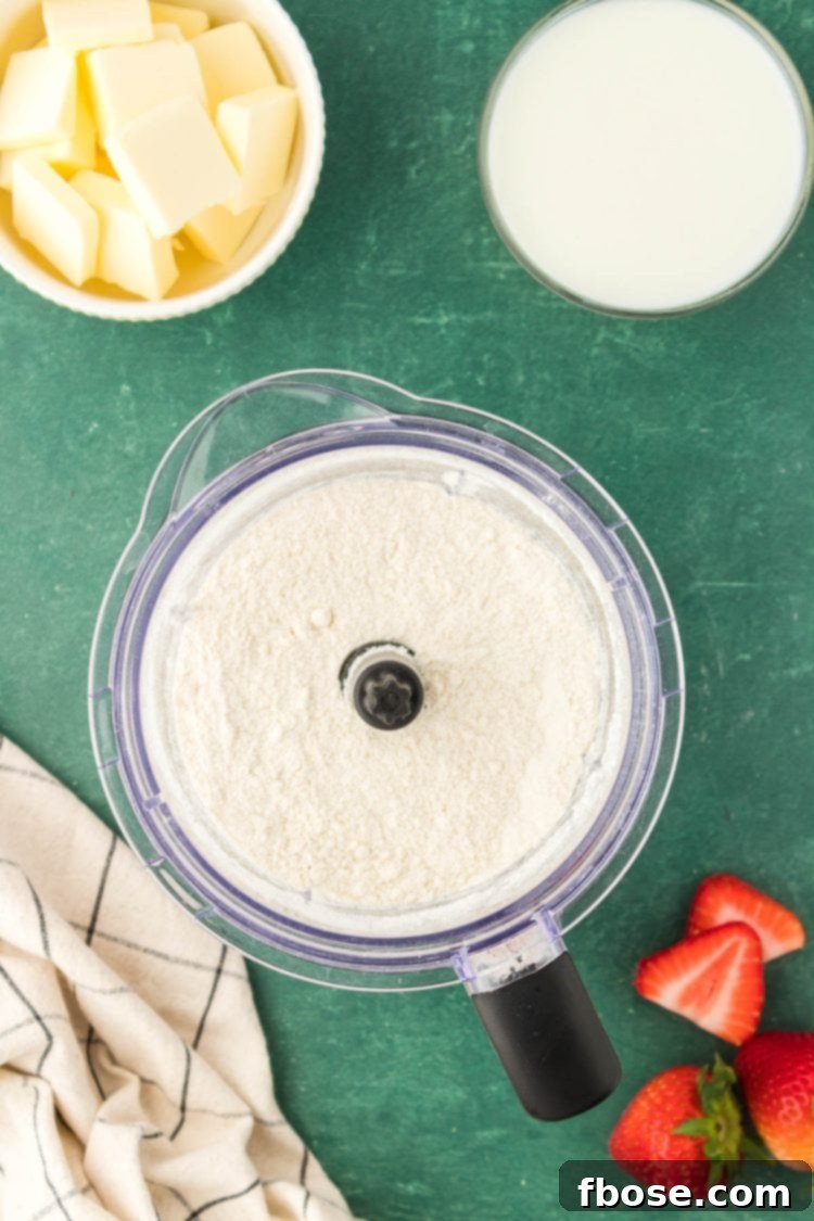Classic Strawberry Cobbler 12 Dry ingredients like flour and sugar precisely measured and placed in a food processor, ready for the next step.