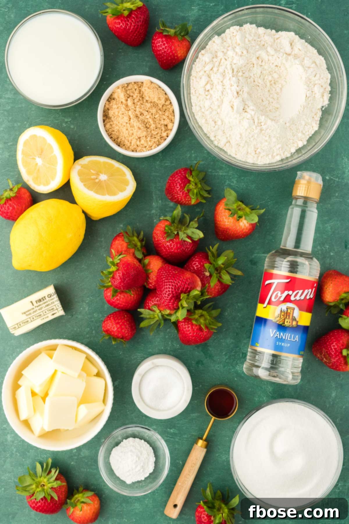 Classic Strawberry Cobbler 4 A curated display of all the fresh ingredients needed to make strawberry cobbler, artfully arranged on a green surface.