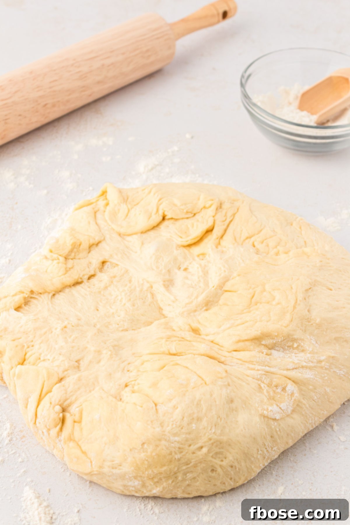 Cinnamon roll dough on a floured surface.