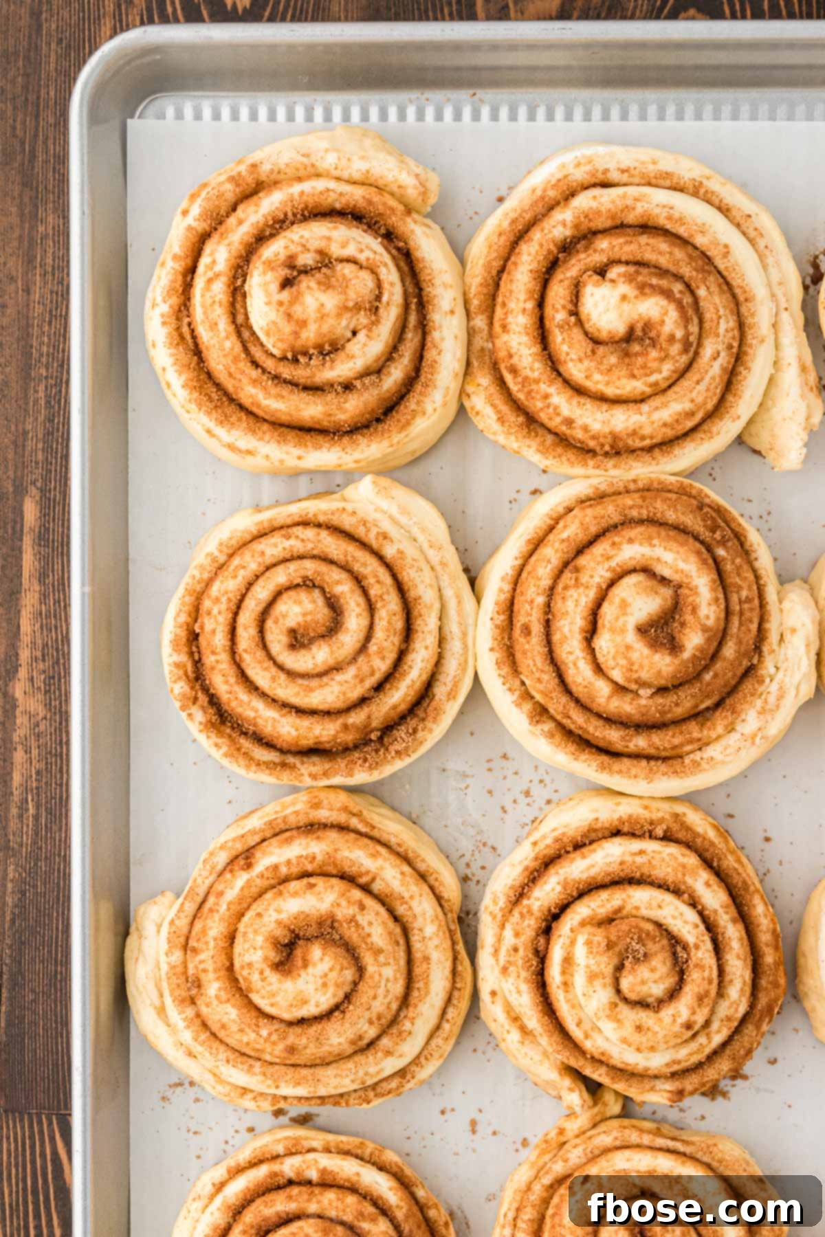 Cinnamon rolls on a parchment lined baking sheet.