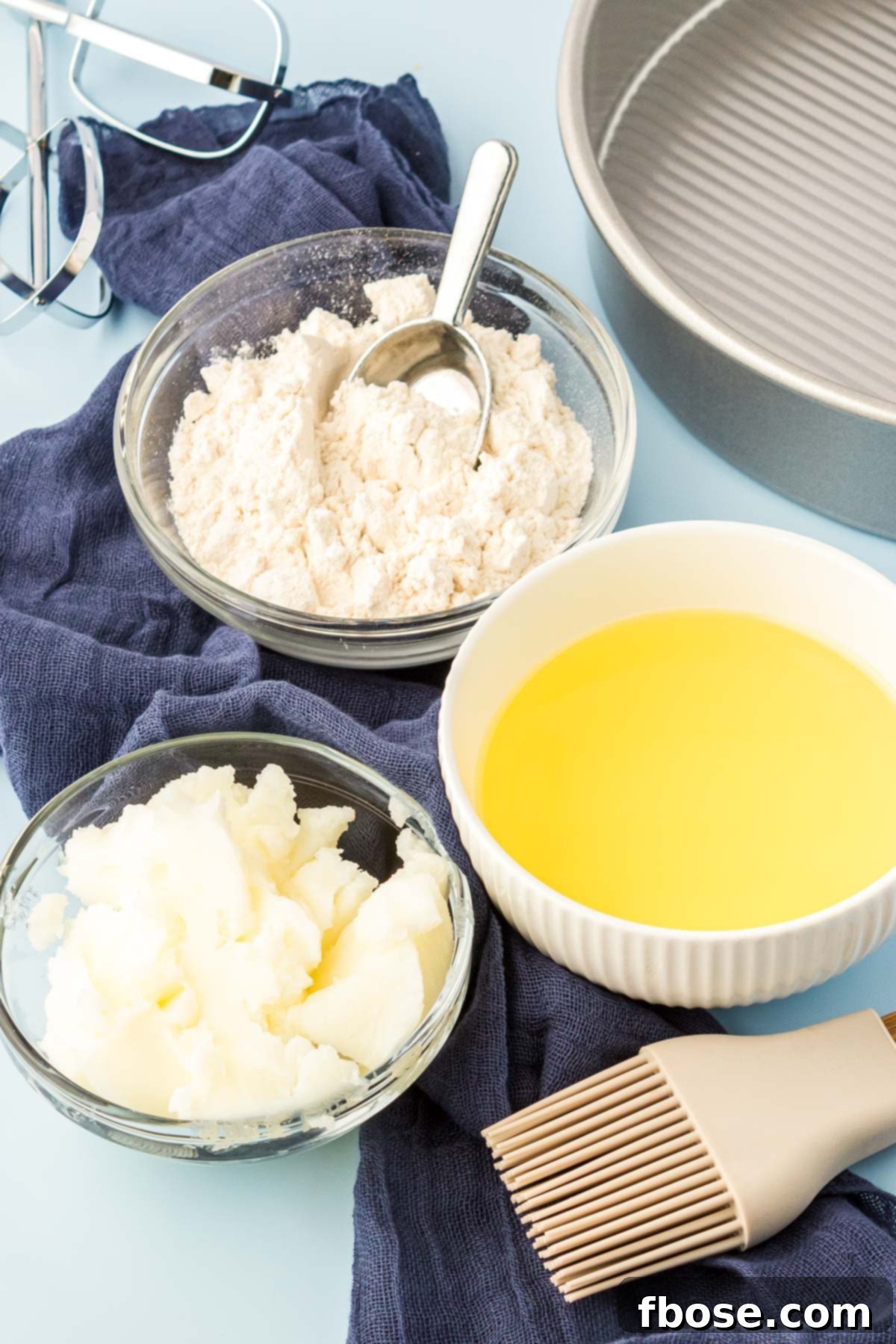 Flawless Cake Release 3 Ingredients to make cake good in prep bowls on a blue surface, clearly showing flour, shortening, and oil.