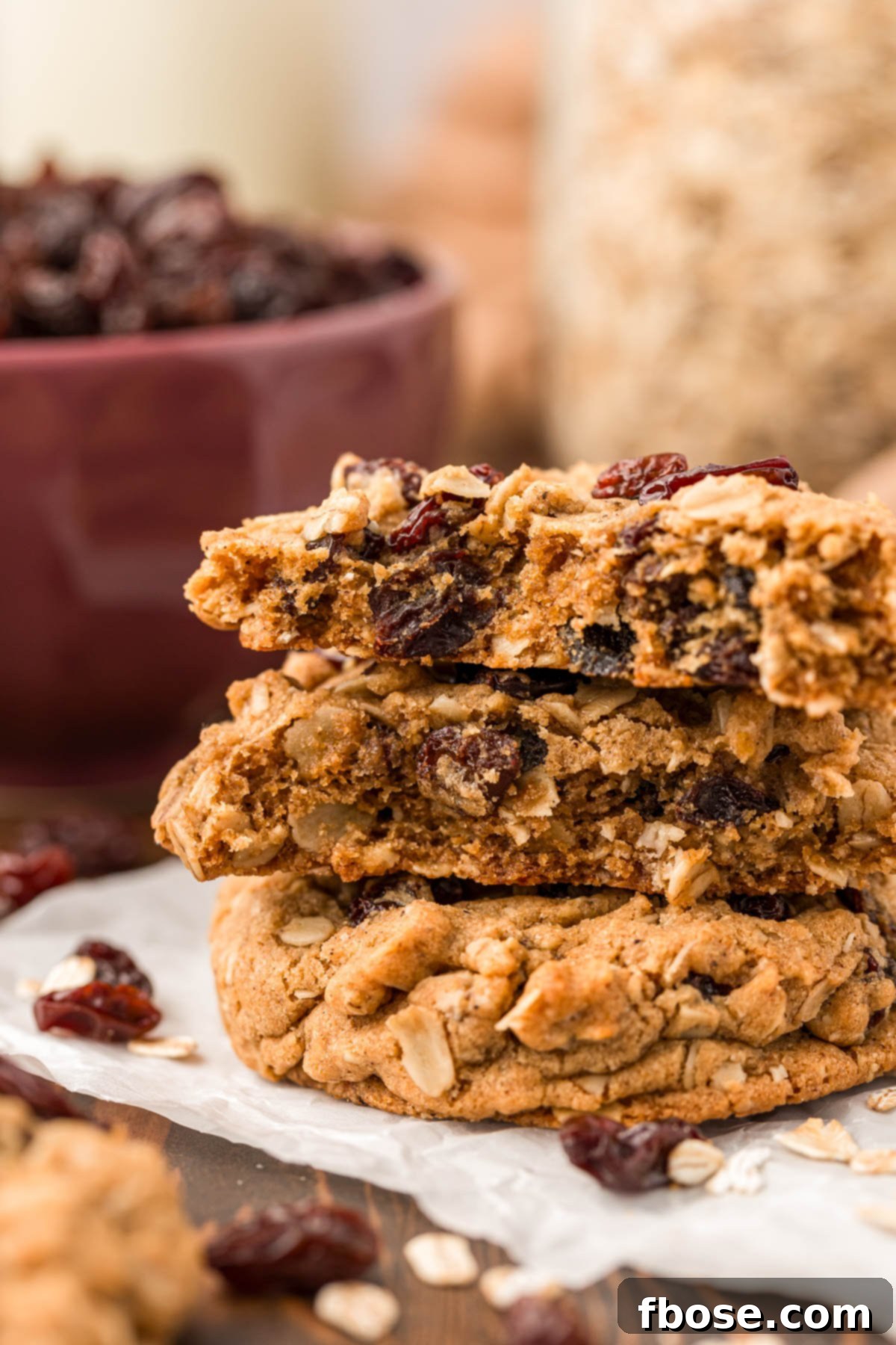 A charming stack of oatmeal raisin cookies, with the top cookies invitingly broken in half to reveal their chewy interiors.