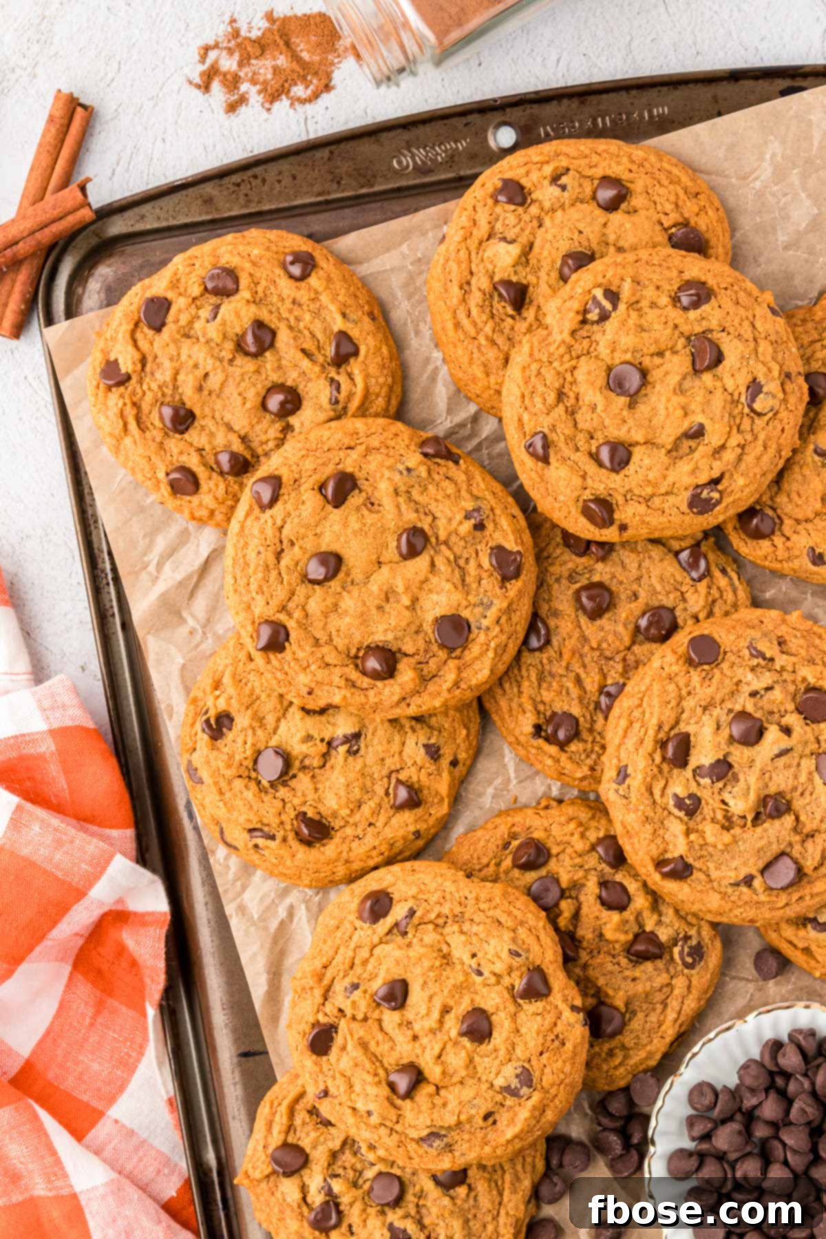 Velvety Pumpkin Chocolate Chip Delights 7 Freshly baked pumpkin chocolate chip cookies cooling on a baking sheet lined with parchment paper.
