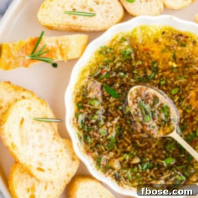 Overhead photo of slices baguette on a white plate with a dish of dipping oil and herbs.